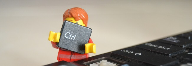 LEGO figurka drží klávesu Ctrl vedle klávesnice počítače.