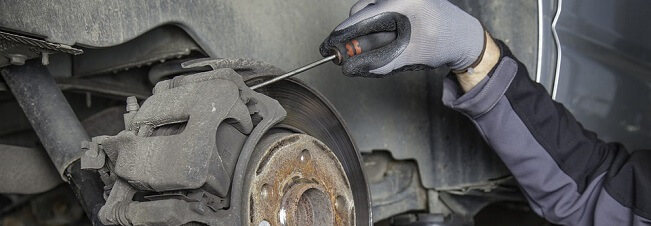 Automechanik provádí servis brzdového systému automobilu.
