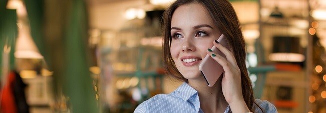Žena telefonuje mobilním telefonem a usmívá se.